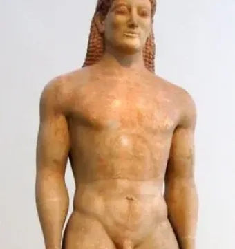 Kroisos Kouros standing nude marble statue with long curly hair and a slight smile