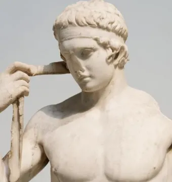 Farnese Diadumenos marble sculpture shown in close-up, with the athletic figure adjusting a band around his head