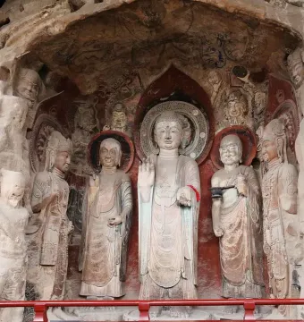 Ancient rock carvings at Huangze Monastery, including a large central haloed statue surrounded by smaller figures in a cave-like recess.
