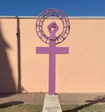 Antimonumenta sculpture in purple, shaped like the Venus symbol with an upright fist on a concrete base.