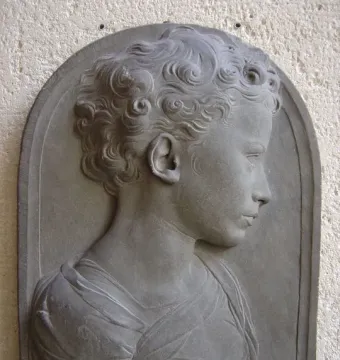 Bust of a Child in profile, showing a curly-haired young figure in draped garments against a dark background.