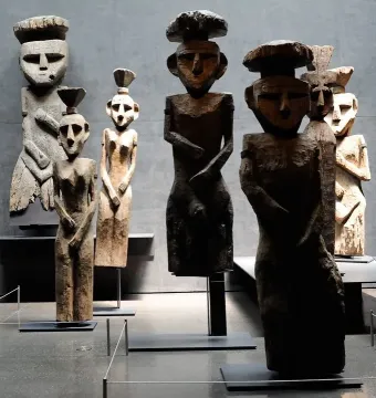 Chemamull wooden figures displayed upright on dark bases in a museum gallery.