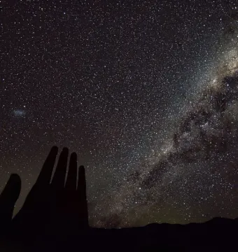 La Mano del Desierto silhouetted against a star-filled night sky and the Milky Way.