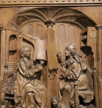 Wooden relief of Saint Luke seated beside the Madonna in an ornate architectural alcove.