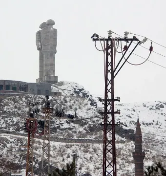 Statue of Humanity, a towering concrete sculpture of two abstract human figures beside a circular building in snowy Kars.