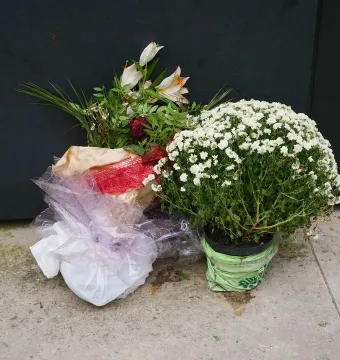 Floral tributes placed before the National Police Memorial, including bouquets and a potted plant with small white flowers.