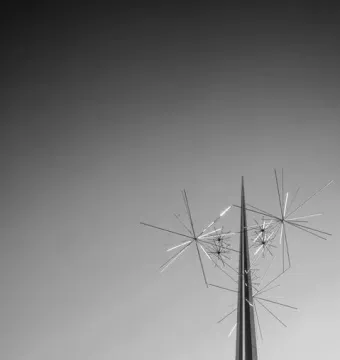 Ad Astra sculpture with slender spire and radiating metal rods against a bright sky.