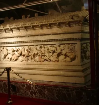 Alexander Sarcophagus with relief carvings, displayed in a glass case with a gold-chain barrier.