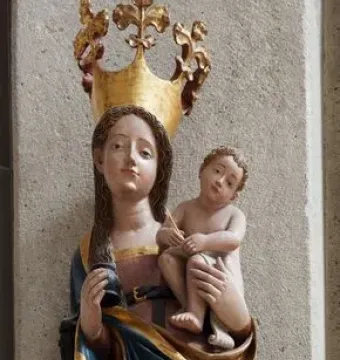 Inkpot Madonna statue of a crowned woman holding a child, with an inkpot and quill, mounted on a decorative bracket.