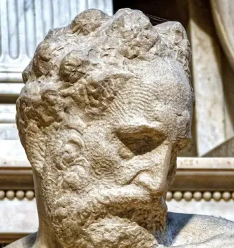 Close-up of Michelangelo’s Medici Chapel sculpture showing a bearded male figure with his head angled downward.