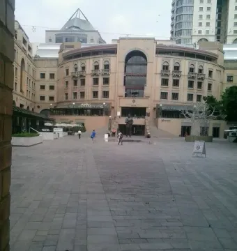 Nelson Mandela statue standing in a paved plaza in front of a large building with an arched window.