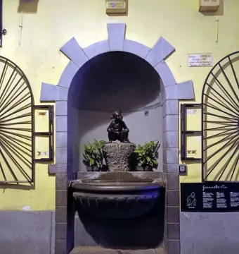 Jeanneke Pis bronze girl statue in a stone alcove with a small fountain below.