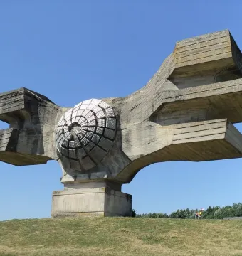Monument to the Revolution of the People of Moslavina on a grassy hill, with a central circular concrete form and broad abstract wings.