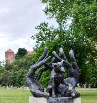 Monument to Dog Jock bronze sculpture of a small dog cradled in large human hands on a stone pedestal in a park.