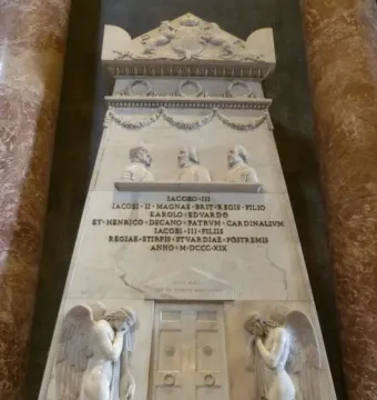 Monument to the Royal Stuarts with white marble figures, busts, and a Latin inscription between red marble columns