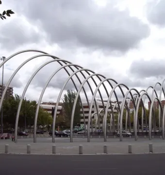 Puerta de la Ilustración, a large modern metal sculpture with curving parallel arches in an urban plaza.