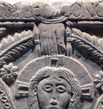 Close-up of the Rachis Altar relief showing a haloed face, an outstretched hand, and carved floral patterns.