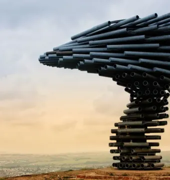 Singing Ringing Tree sculpture made of dark metal pipes on a hilltop overlooking the town and fields below