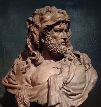 Bust of Hercules shown in side profile, with a curly beard, wrinkled brow, and lion skin draped over the head and shoulders.