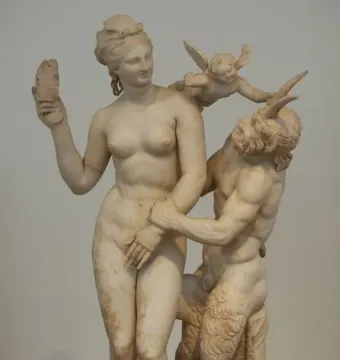 Marble sculpture of Aphrodite with Pan and Eros, showing a nude woman holding a sandal as a horned satyr reaches toward her with a small winged figure on his shoulder.