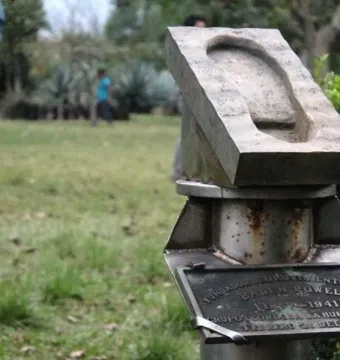 Weathered stone footprint monument on a rusty metal pedestal with a commemorative plaque.