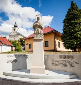 Stone statue of St. John of Nepomuk holding a crucifix, standing on a pedestal with a halo of stars around his head.