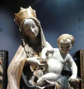 Beautiful Madonna of Wrocław holding a nude child on her left hip and offering a small round object.