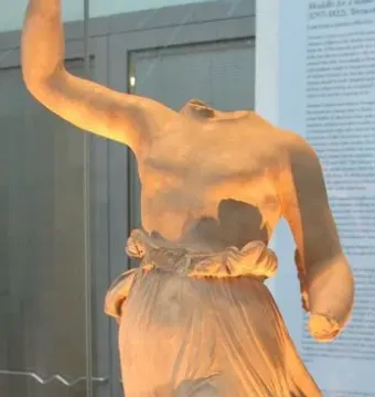 Hebe by Antonio Canova, a headless female statue with one arm raised and draped lower body in a museum display case.