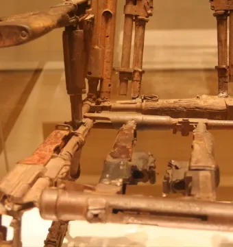Close-up of Throne of Weapons made from rusted firearms and corroded metal parts behind glass.