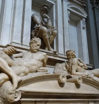 Michelangelo’s Dusk, showing two reclining marble figures beneath a seated figure in the Medici Chapel.