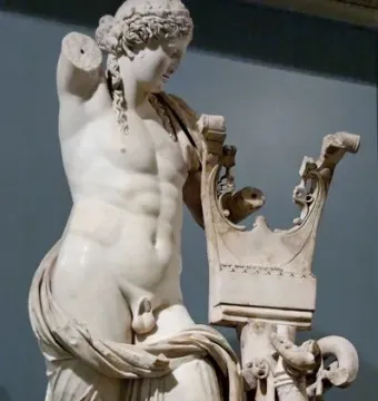 Apollo of Cyrene marble statue with a lyre-shaped support, missing its right arm and draped around the lower body.