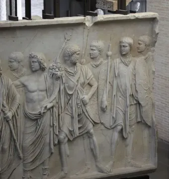 Cancelleria Reliefs showing a marble panel with male figures in a military procession, some wearing tunics and togas and others carrying shields and spears.
