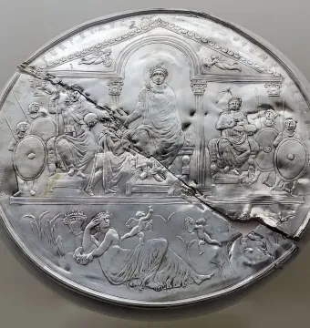 Disc of Theodosius showing a damaged silver relief with an enthroned figure, attendants, and a reclining female figure among wheat stalks.