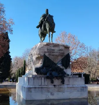 Bronze equestrian statue of General Martínez-Campos on a tiered stone pedestal reflected in a pool.