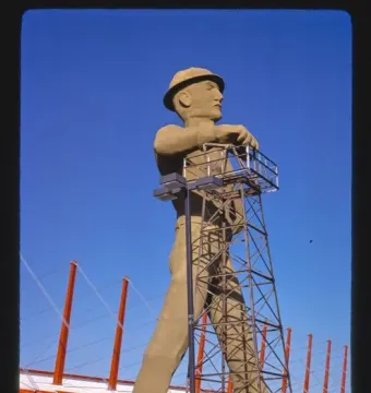Golden Driller statue standing by a metal derrick structure in Tulsa, Oklahoma.