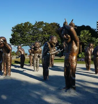 A-maze-ing Laughter sculptures of bald men with laughing expressions in a waterfront park.