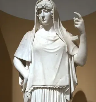 Giustiniani Hestia, a white marble female statue in draped garments with one hand on her hip and the other raised.