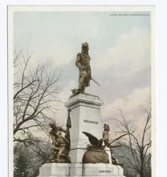 Tadeusz Kościuszko statue on a tall white pedestal with bronze figures and an eagle at the base.