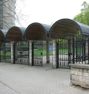 Monument of Common Martyrdom with four arched structures, stone pillars, and wrought-iron gates beside a walkway.