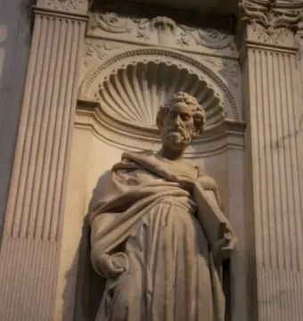 Saint Peter statue of a bearded man holding a scroll or book in a decorative niche.