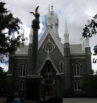 Seagull Monument with a golden bird sculpture in front of the Assembly Hall\'s grey stone facade and white spires.