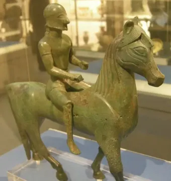 Armento Rider bronze statuette of a helmeted rider on a horse, shown on a clear stand.