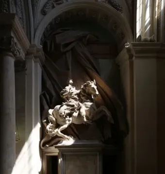 The Vision of Constantine, a white marble equestrian statue lit by sunlight inside an ornate niche.