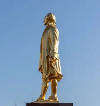 Alexander Hamilton Memorial statue of a man in period clothing holding a tricorn hat on a dark pedestal.