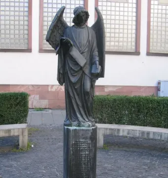 Frankfurter Engel sculpture showing a winged figure in flowing robes holding a scroll and a small book or box.