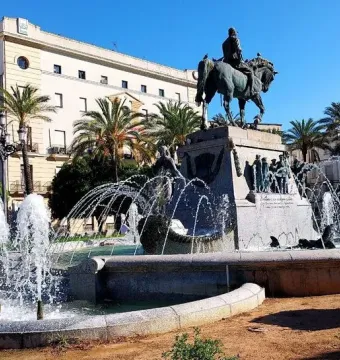 Bronze equestrian statue of Primo de Rivera on a stone pedestal in a fountain with arcing water jets.