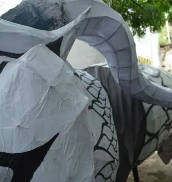 Alebrije sculpture with crinkled white surface, black stripes, and a curved segmented horn