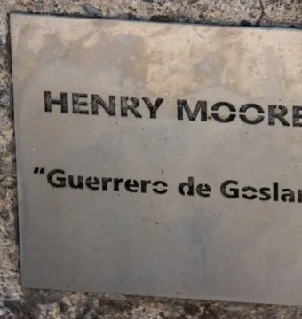 Metal plaque on a rough stone wall reading Henry Moore and Guerreros de Goslar.