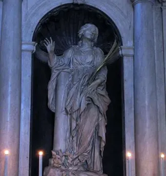 St. Bibiana marble statue in an arched niche, holding a leafy frond and raising one hand.