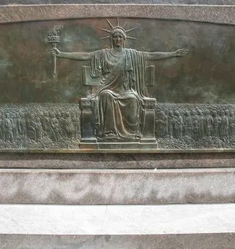 Heald Square Monument bronze relief showing a seated female figure with a torch, flanked by crowds of figures.